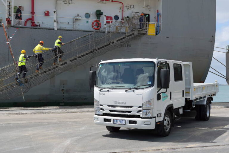 Isuzu truck at dock with ship in background