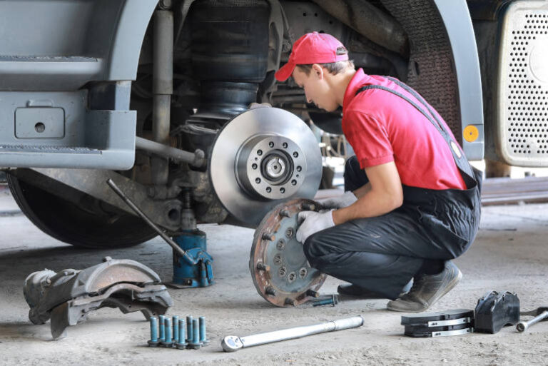 A mechanic repairs a truck. Replace brake disc and pads