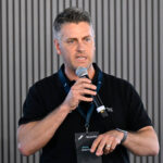 MELBOURNE, AUSTRALIA - MARCH 05: Brenton Gill, Co-Founder and CEO, Radaro addresses the crowd during the HERE Technologies conference in the Chicane Pavilion at Albert Park Grand Prix Circuit on March 05, 2026 in Melbourne, Australia. (Photo by Adam Trafford/Getty Images for HERE Technologies)